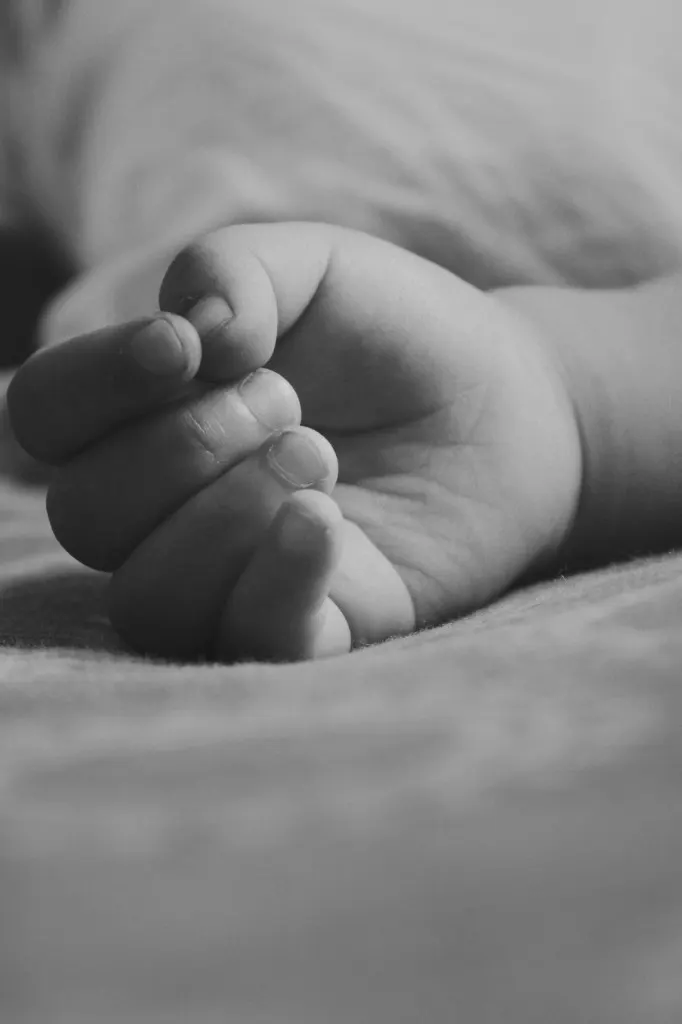 A baby’s hand resting on a blanket